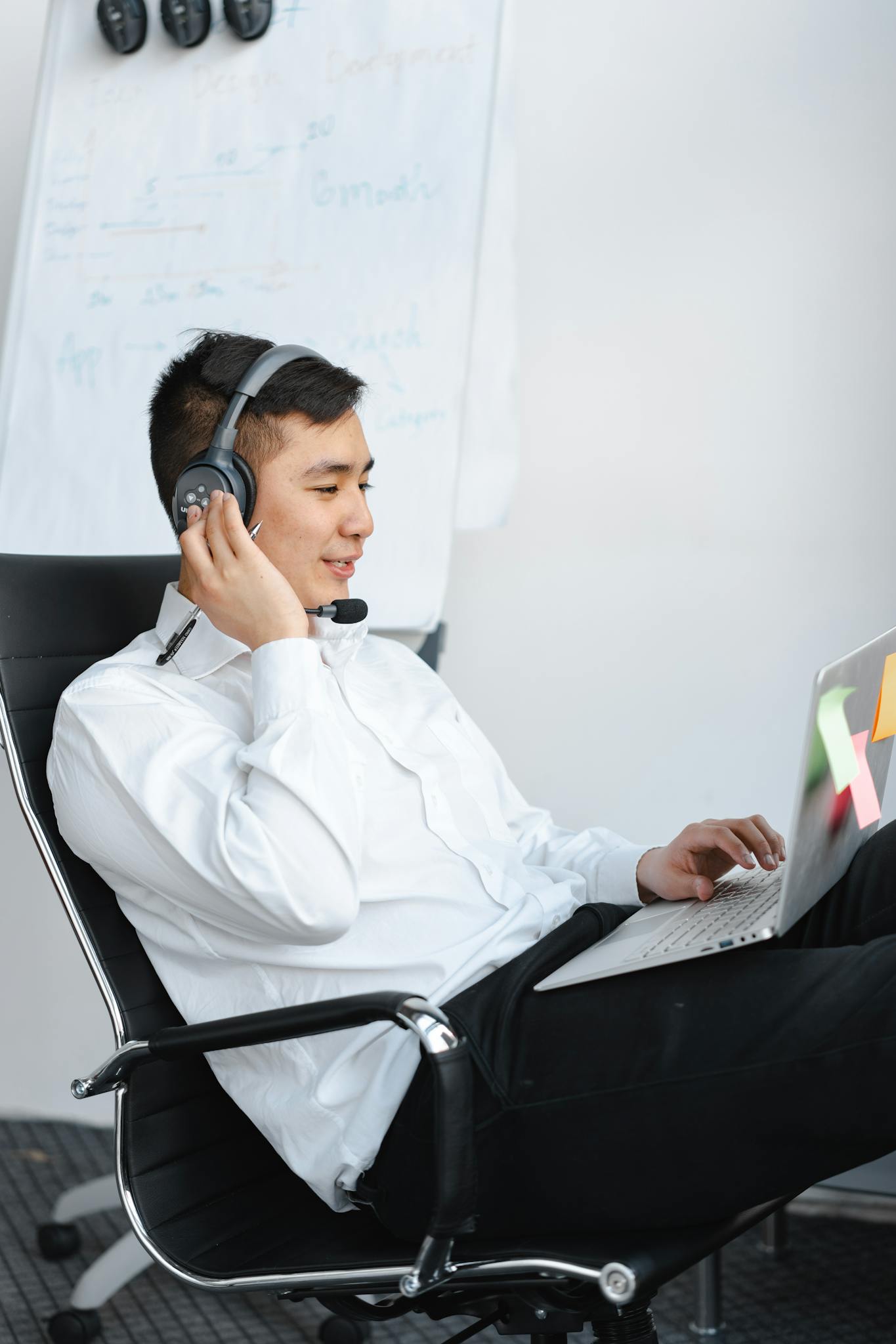 Professional Asian call center agent engaging in a remote customer support session with a laptop and headset.